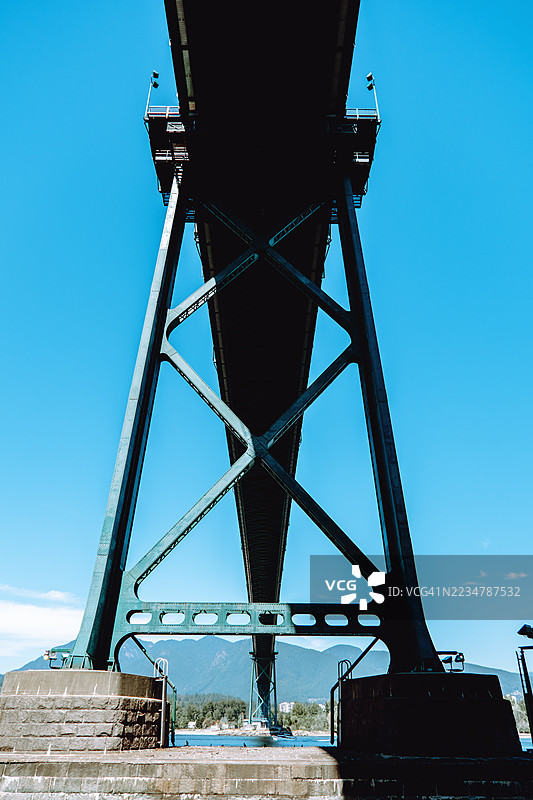 在高大的金属桥下，蓝天和美丽的自然环境环绕着。图片素材