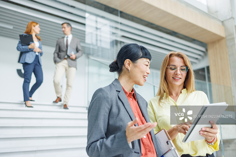 商务女性在现代办公室使用平板电脑讨论图片素材