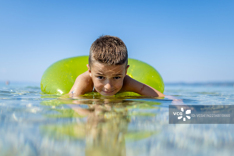 年轻人在清澈的海洋中漂浮在明亮的游泳圈上游泳图片素材