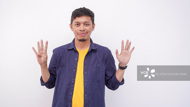亚洲男子在孤立背景下用手指指向上方并展示数字。图片素材