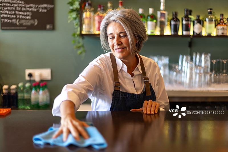 成熟的酒保在清洁酒吧的台面图片素材