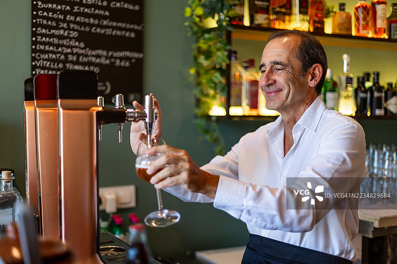 酒吧调酒师在餐厅酒吧倒啤酒入杯图片素材
