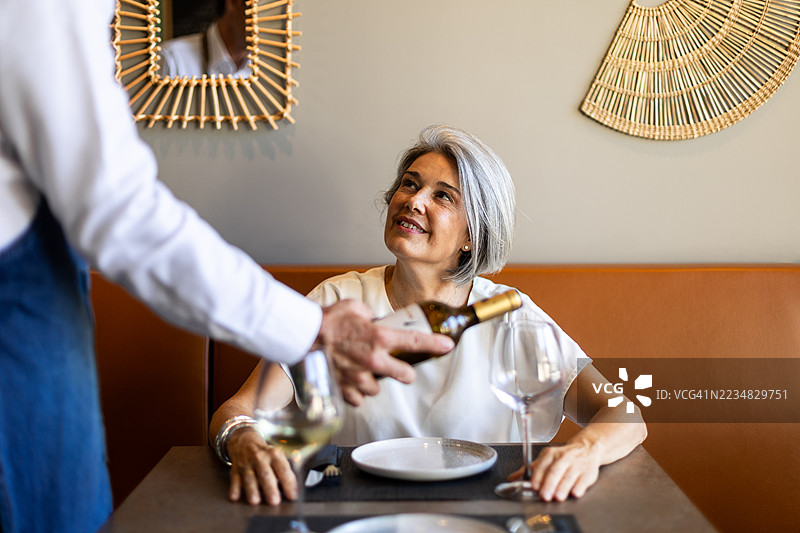 服务员在餐厅向微笑的顾客展示酒瓶图片素材