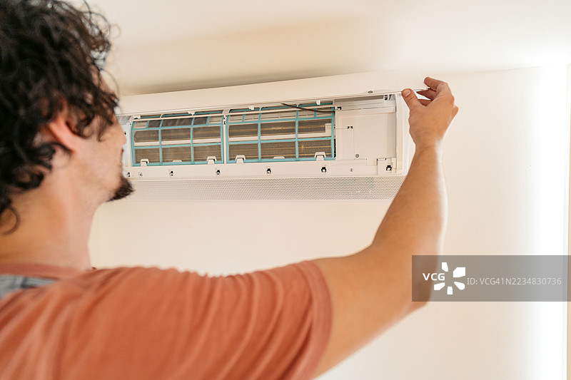 中年男性电工在公寓里修理空调图片素材