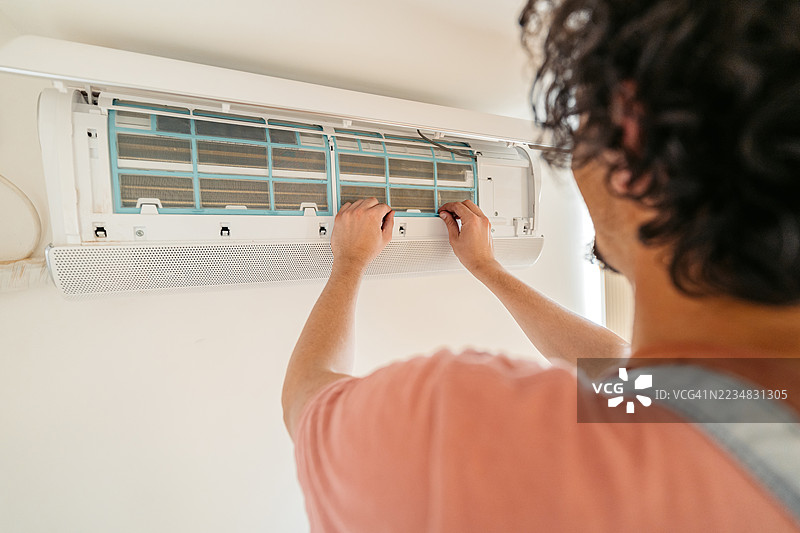 中年男性电工在公寓里修理空调图片素材