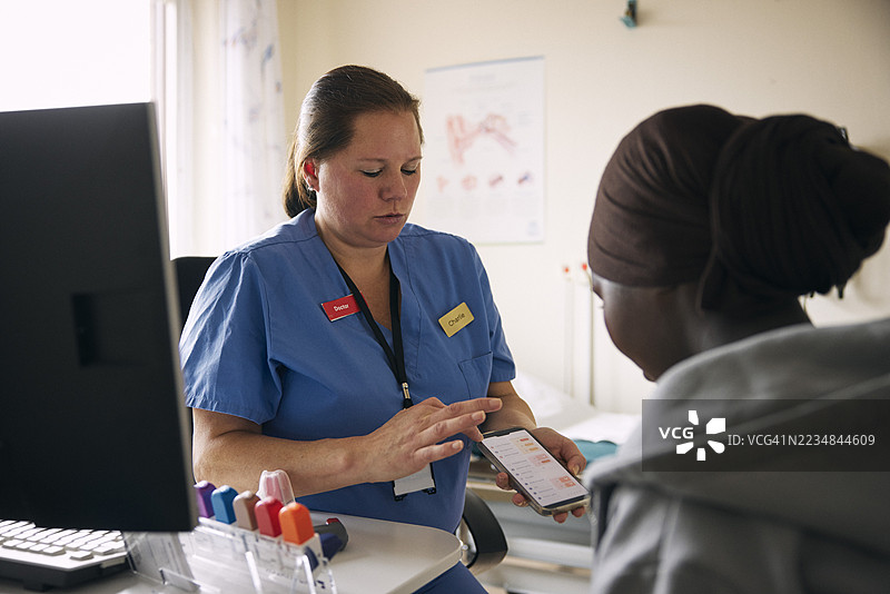 女儿科医生在医院里通过智能手机向女孩解释医疗状况的待办事项。图片素材