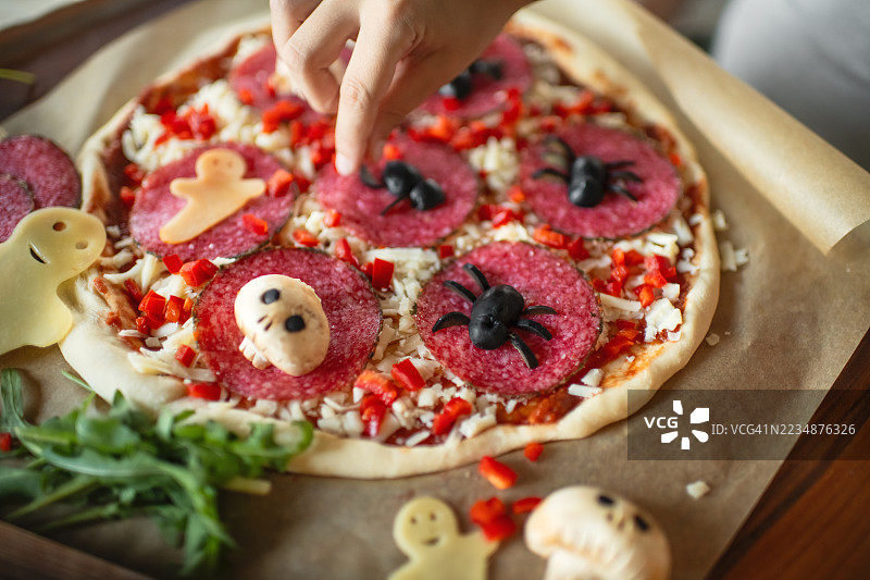 男孩在厨房为万圣节制作披萨图片素材