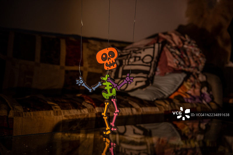 色彩斑斓的骷髅木偶悬挂在玻璃桌上并映出倒影图片素材