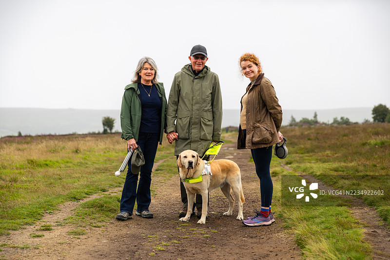 英格兰乡村阴天里一家三口和导盲犬的肖像图片素材