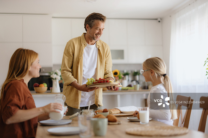 快乐的家庭在厨房一起享用早餐图片素材