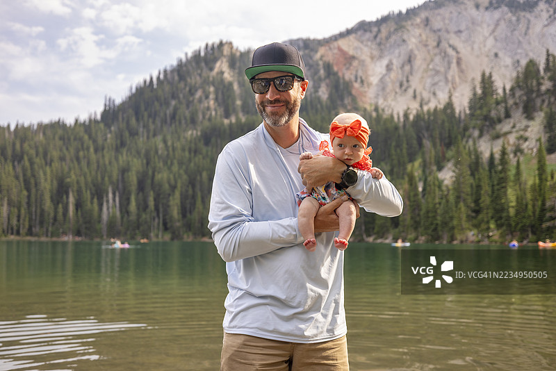 一位父亲和他的婴儿女儿在山湖边图片素材