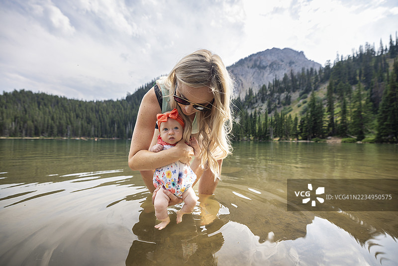年轻母亲与她的宝宝在山湖边图片素材