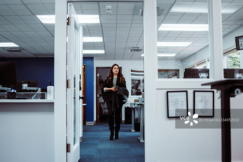 下班时，一位女商人走在办公室里图片素材