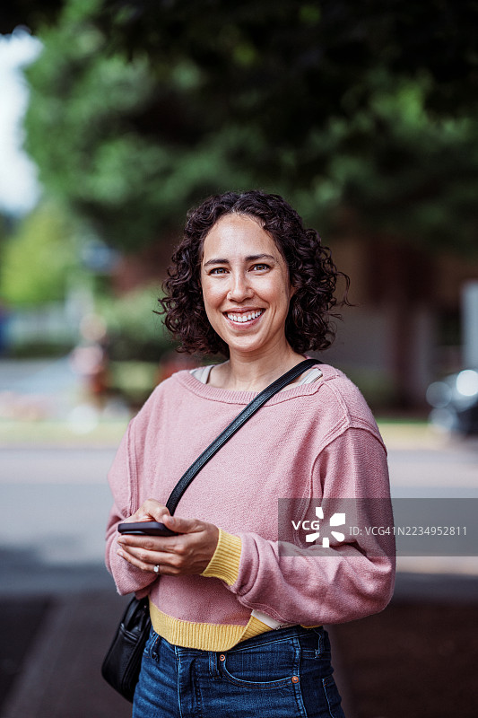 微笑的女性在银行外使用手机图片素材