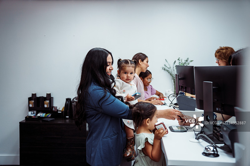 Hispanic woman with baby at bank reception desk图片素材