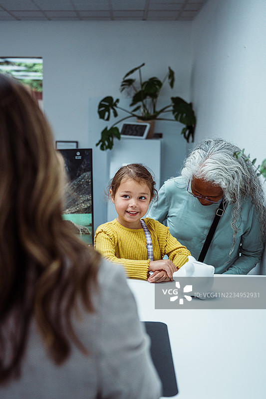 小女孩与银行出纳员交谈，手里拿着储蓄罐图片素材