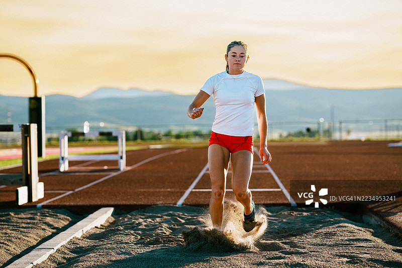 田径运动员在跳远热身尝试中落入沙坑图片素材