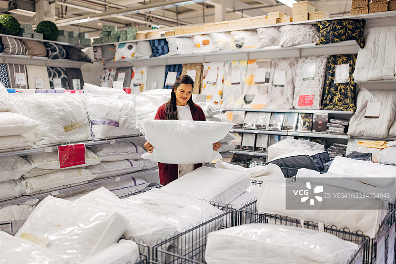 无忧无虑的亚洲女性在现代家居店挑选卧室枕头图片素材