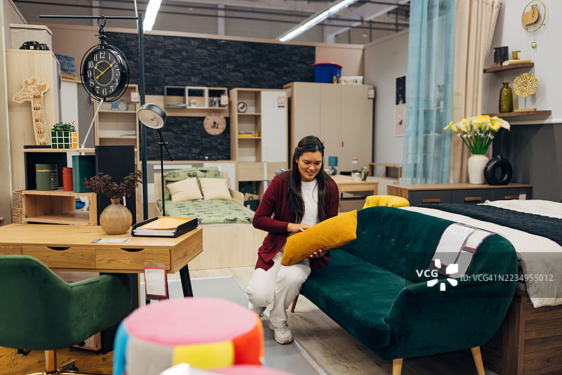 微笑的亚洲女性在家具店检查卧室氛围的沙发布置图片素材
