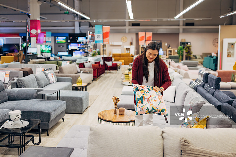 亚洲女性在家具店查看沙发床和装饰性抱枕图片素材