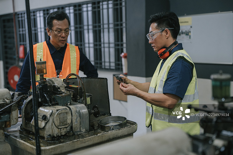 亚洲主管在工厂观察机械师用卡尺测量金属部件图片素材