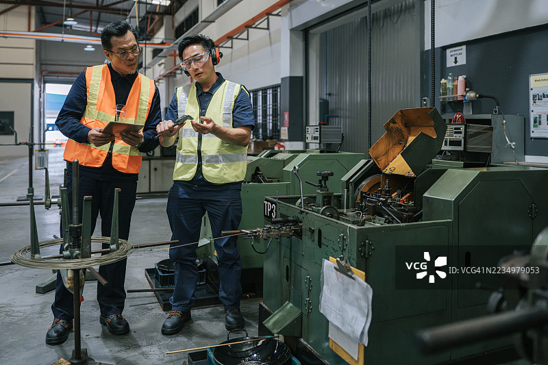 亚洲主管和技术员在工厂检查螺丝攻牙机图片素材