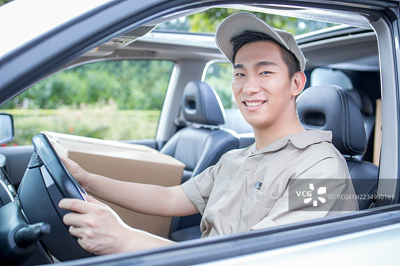 微笑的快递员坐在车里手里拿着包裹图片素材