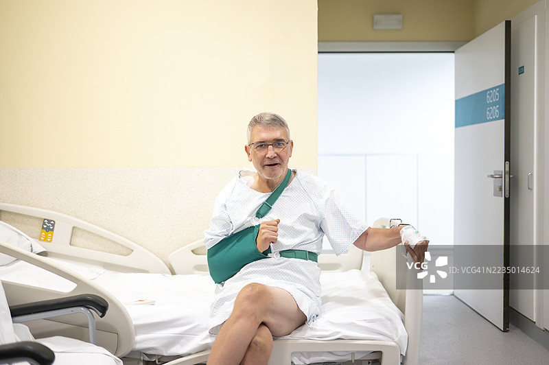 坐在医院床上的老年男性患者，佩戴绿色臂吊带。图片素材