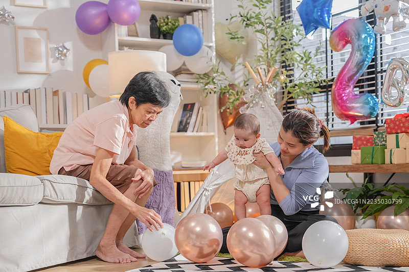 庆祝生日派对的多代亚洲家庭，祖母、父母和侄子一起庆祝，享受蛋糕、气球和活动装饰，欢乐有趣，享受美好时光。图片素材