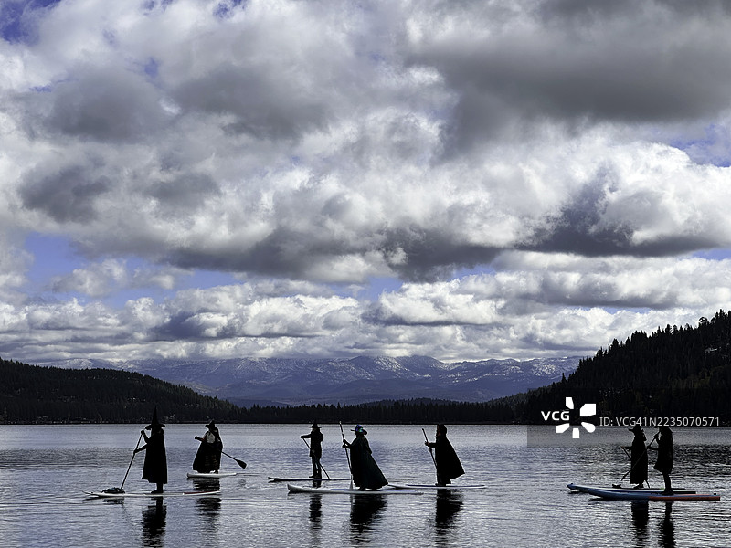 女巫们在万圣节的暴风雨山湖上划船图片素材
