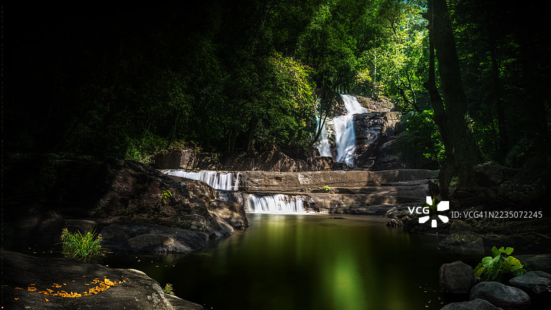 雄伟的瀑布倾泻而下，穿过郁郁葱葱、幽暗的森林，构成一幅宁静的自然景观，位于印度特里凡得琅。图片素材