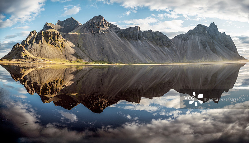 冰岛宁静湖水下壮丽的山脉倒影与广阔的天空图片素材