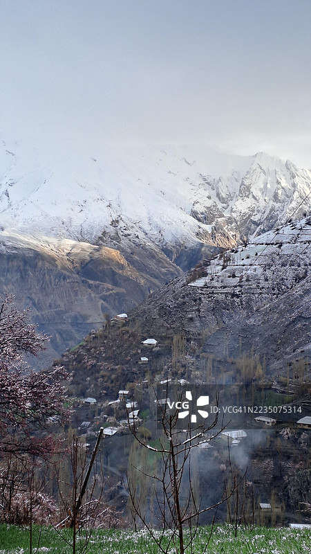 雄伟的雪山和一个坐落在柔和天空下山谷中的村庄图片素材