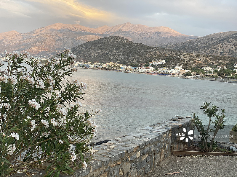 日落时分，坐落在山脉和宁静海湾旁的海滨小镇全景图片素材