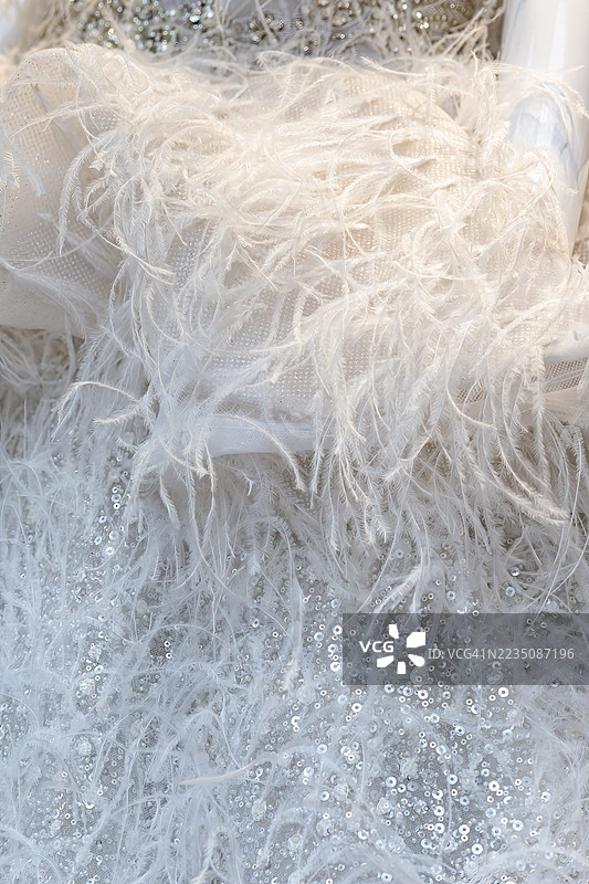 精致羽毛和闪亮亮片的点缀，优雅的白色织物特写，营造出奢华而富有质感的背景图片素材