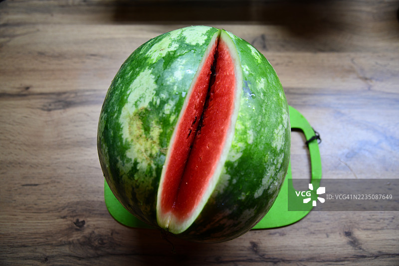 新鲜成熟的西瓜特写，切出一片，静静地放在木桌上，准备享用这款清爽的夏季水果。图片素材