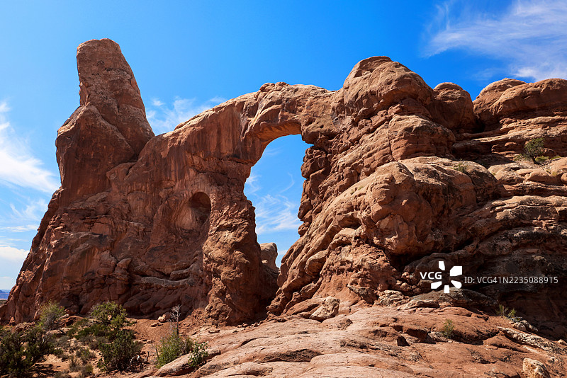 雄伟的岩石 formations 和自然拱门在沙漠景观中高耸于晴朗的蓝天之下。图片素材