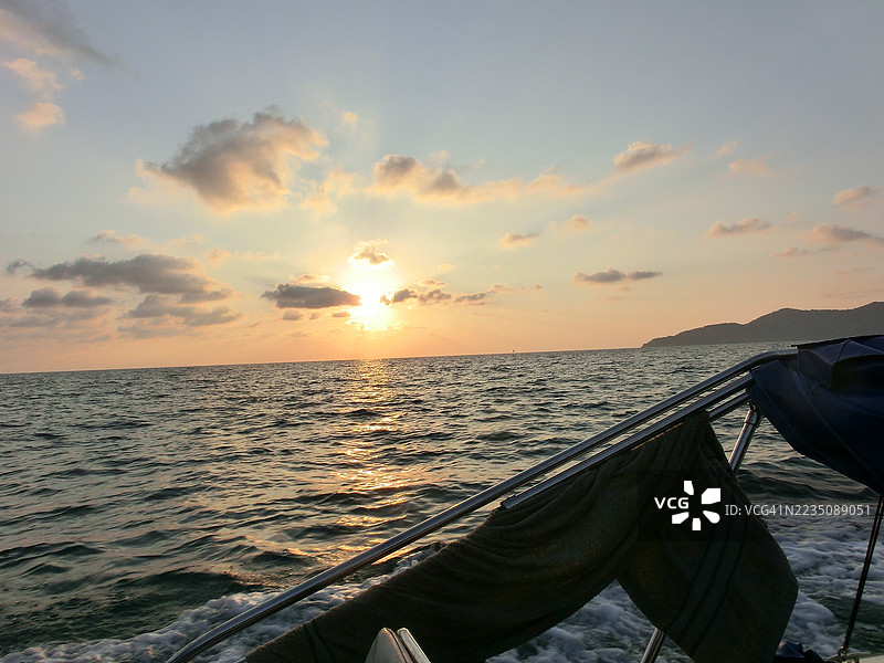 从船上俯瞰海洋上绚丽的日落景色，温暖的光线在水面上反射。图片素材