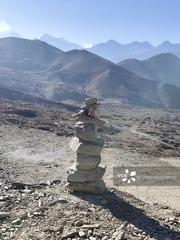 堆叠的岩石，称为石堆，在晴朗的天空下矗立于喜马拉雅山脉的壮丽背景中。图片素材