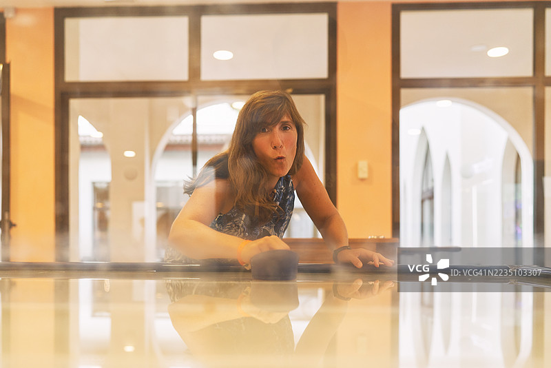 女性专注于在游戏室里打空气曲棍球图片素材