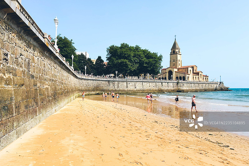 西班牙阿斯图里亚斯吉洪的圣洛伦佐海滩和圣佩德罗教堂。图片素材