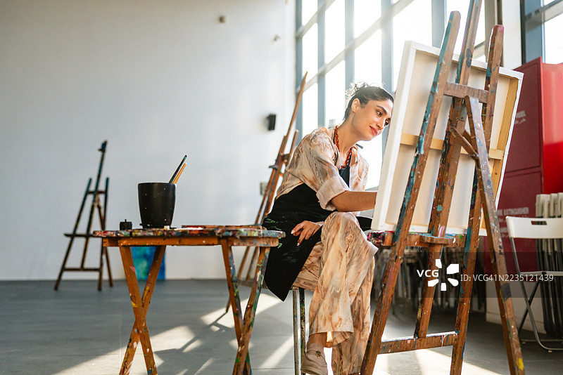 年轻女性画家在明亮的工作室创作艺术作品图片素材