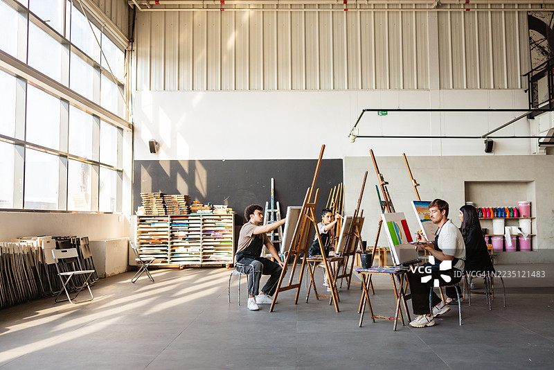 多元化的艺术家团队在明亮的工作室中绘画图片素材