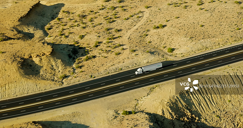 犹他州沙漠中，半挂卡车行驶在70号州际公路上的电影感航拍视角图片素材