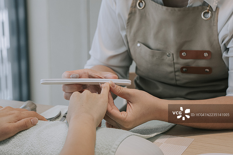 亚洲专业美甲师在修剪客户指甲，进行美甲护理。图片素材