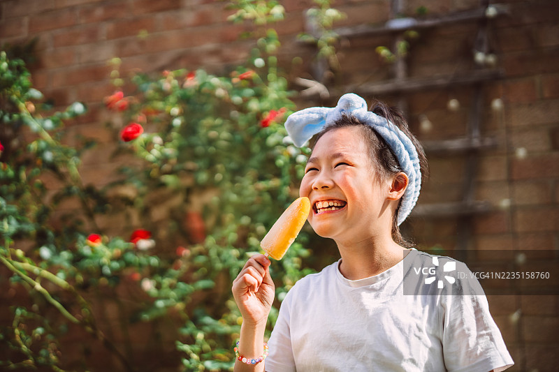 快乐的孩子在阳光明媚的夏日户外享受橙色冰棒图片素材
