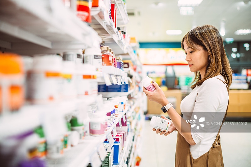 女性在商店过道中选购维生素和补充剂图片素材