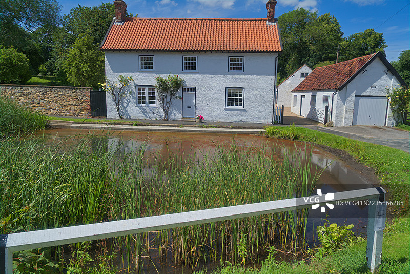 位于约克郡东部贝弗利附近的比肖普伯顿风景如画的村庄中的鸭塘附近的房屋。图片素材