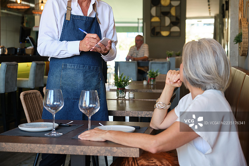 服务员在餐厅为一位成熟的女性点餐图片素材