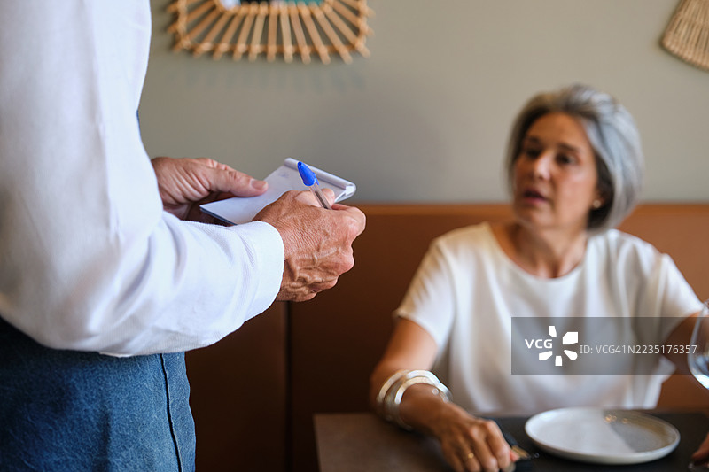 服务员在餐厅为一位成熟的女性点餐图片素材